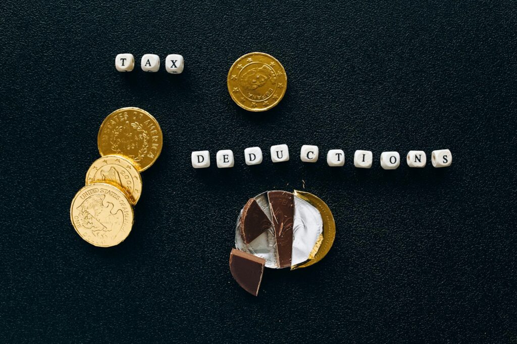 The words tax deductions spelled in beads beside gold coins and a coin pie chart, representing the ordinary-income tax due on traditional retirement withdrawals